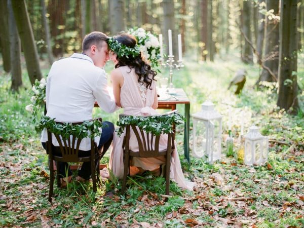 Braut und Bräutigam sitzen an einem Tisch im Wald