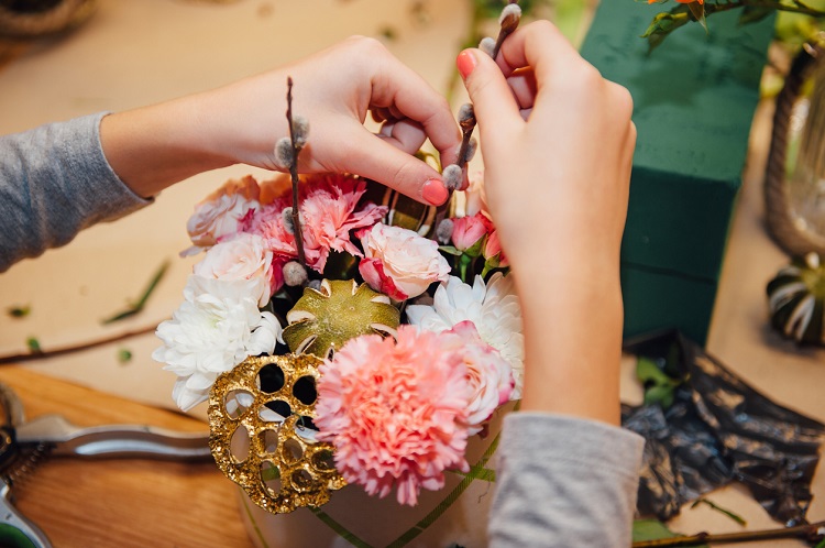 Zwei Hände dekorieren einen Blumenstrauß