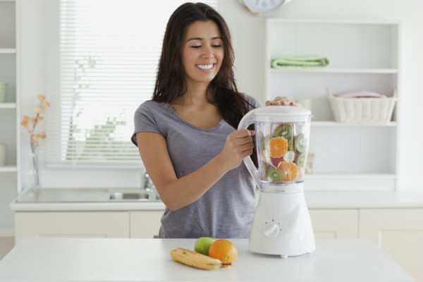 Junge Frau beim Smoothie mixen