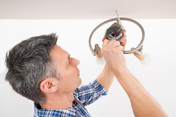 Mann beim Anschließen einer Deckenlampe