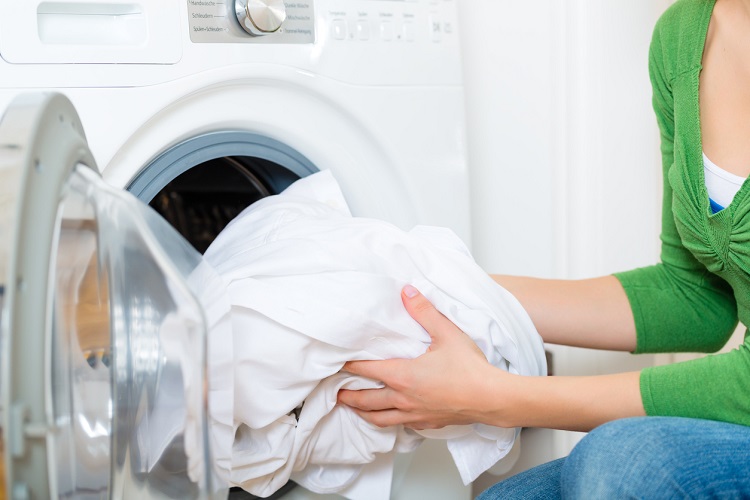 Weißer Vorhang wird in die Waschmaschine gegeben