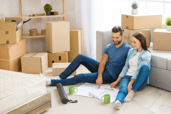 Ein Paar, das in einer Wohnung mit Umzugskartons sitzt und einen Umzug plant