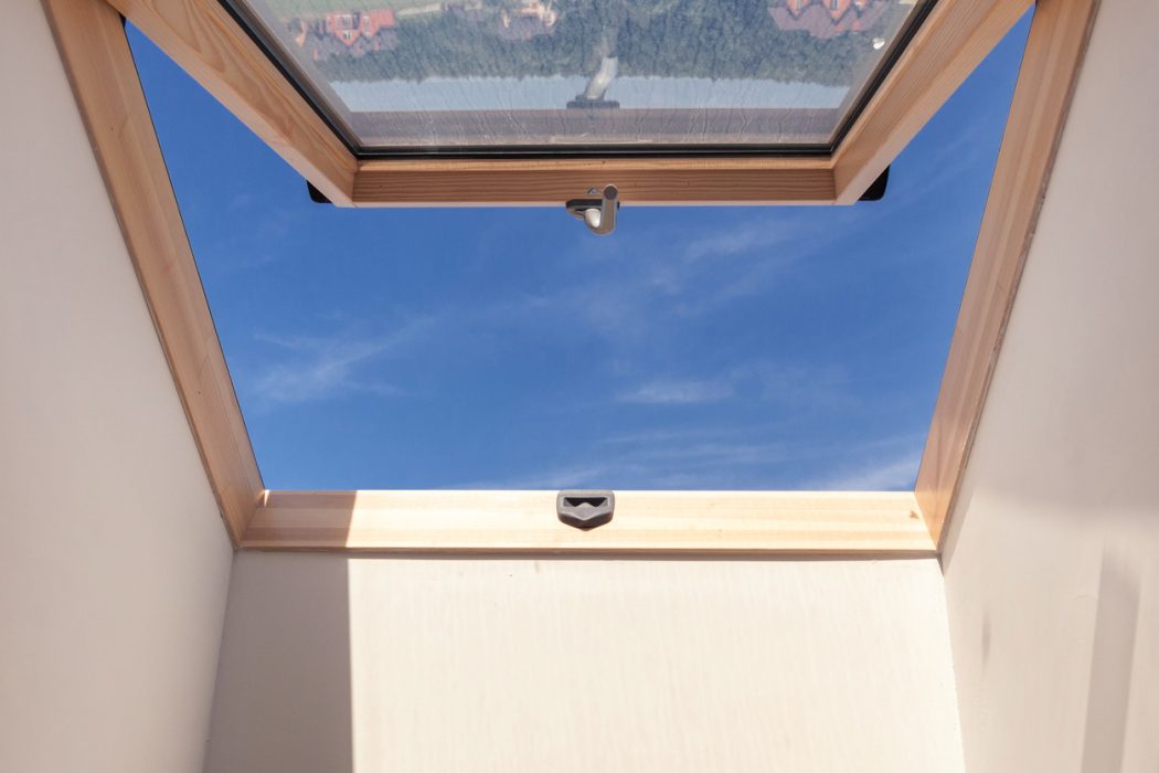 Blick in den Himmel durch halb geöffnetes Dachfenster