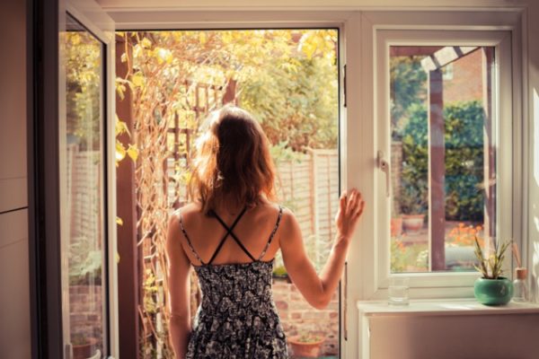 Frau lüftet ihr Zimmer im Sommer