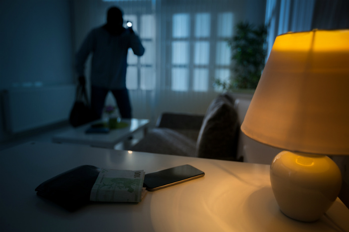 Einbrecher mit Taschenlampe in wenig beleuchteten Raum