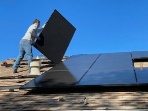 Ein Mann verlegt ein Solar-Panel auf einem Dach